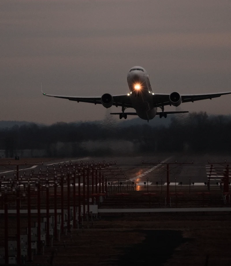 Aircraft taking off at twilight above runway lights